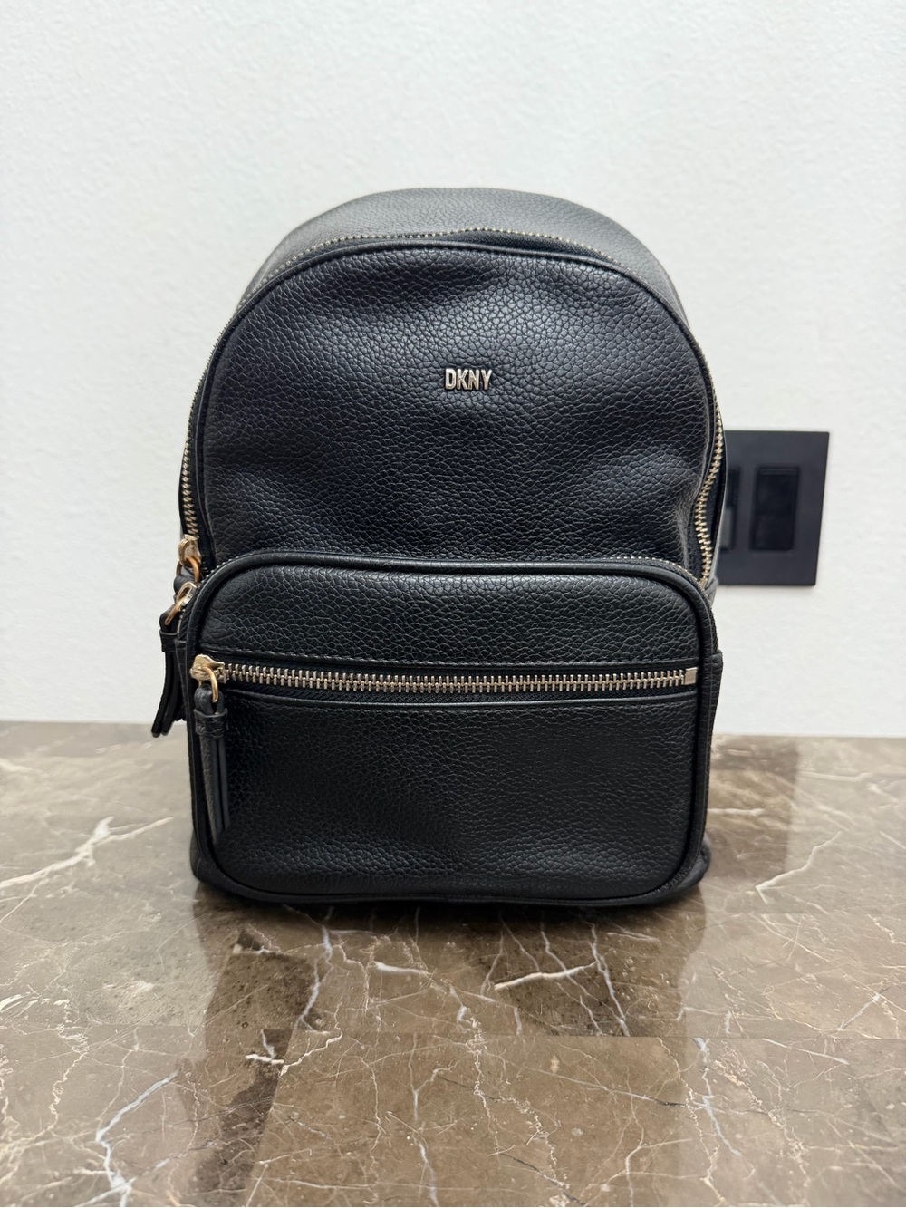 Black pebbled leather DKNY Backpack accented with subtle gold-tone hardware